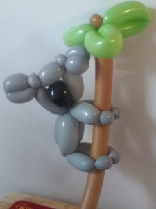 Koala bear with a large black nose climbing a palm tree twisted for a children's event