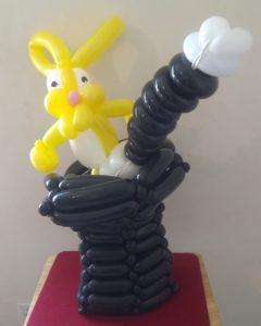 Yellow rabbit twisted balloon in a magician's black balloon hat with a balloon magic wand