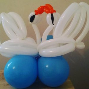 Kissing swan balloons on top of round blue balloons used as balloon decorations. 