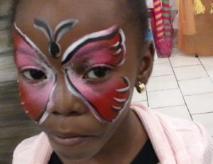 Girl face painted as a pink butterfly for a kid's party